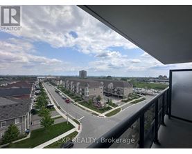 A view from a balcony looking out at a street lined with houses and cars.