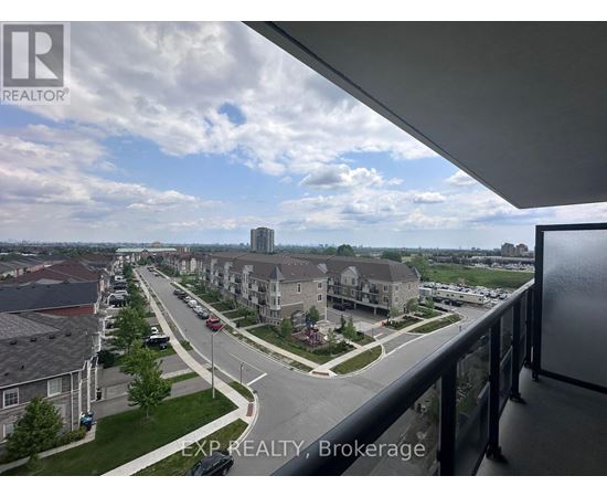 A view from a balcony looking out at a street lined with houses and cars.