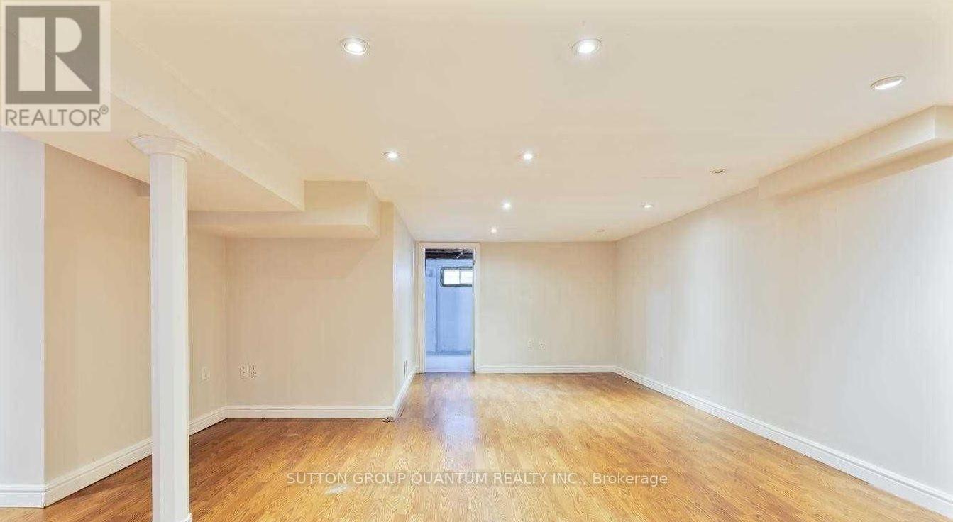 A spacious room with wooden floors and white walls, featuring a doorway to another room.