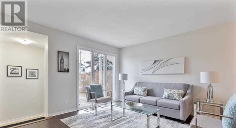 A living room with a grey couch and a glass table.