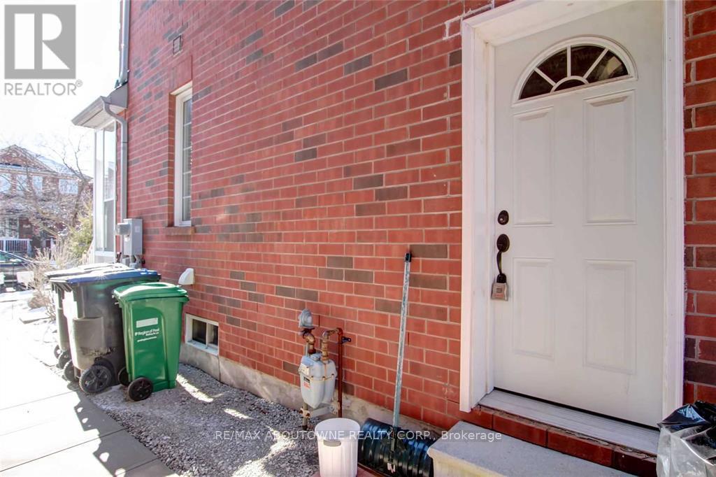 A red brick house with a white door and a green trash bin.