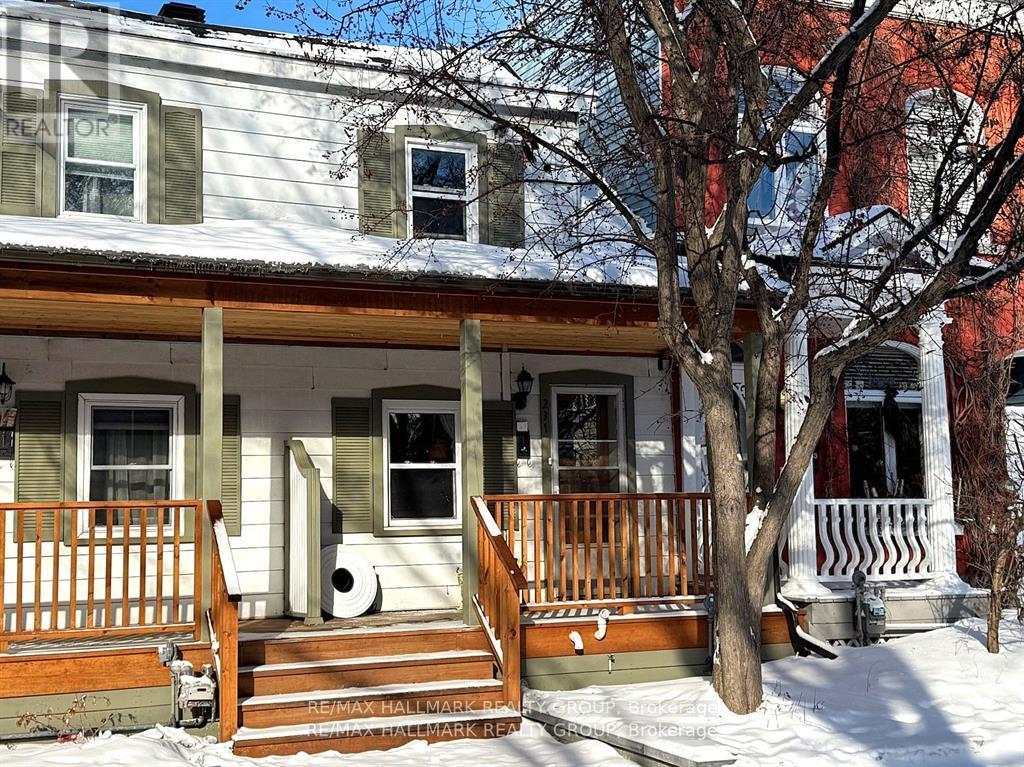 A house with a porch and a tree in front of it.