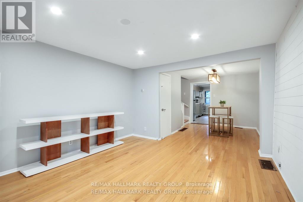 A spacious room with wooden floors and white walls, featuring a long shelf with multiple compartments and a small table with a plant on it.
