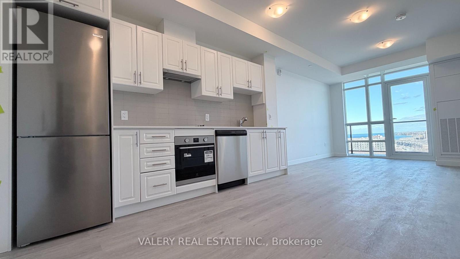 A kitchen with white cabinets and a stainless steel refrigerator.