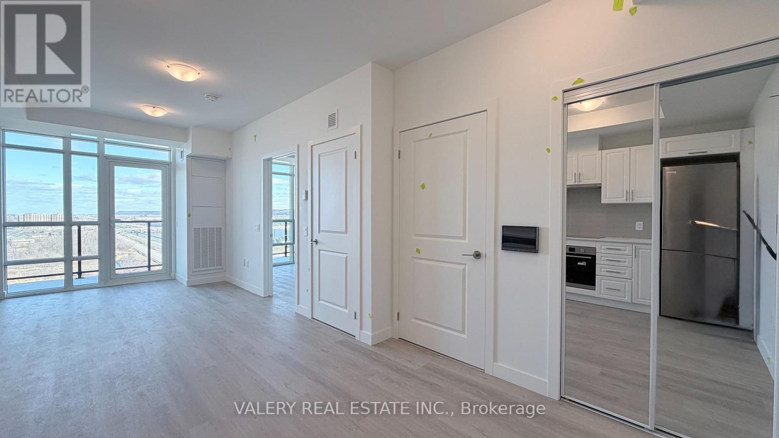 A spacious kitchen with white cabinets and a refrigerator is visible.