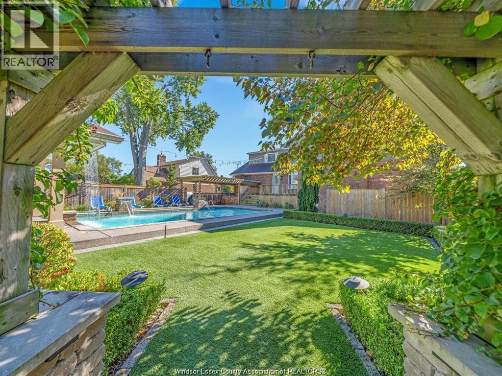 A backyard with a pool and a wooden pergola.