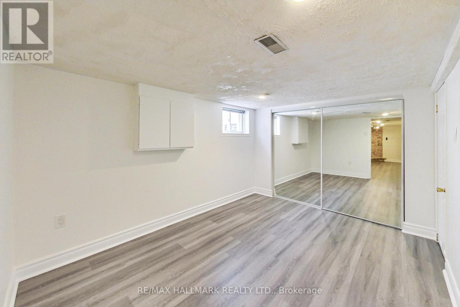 A spacious room with wooden flooring and white walls.
