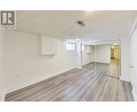 A spacious room with wooden flooring and white walls.