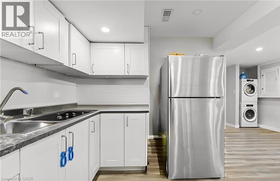 A modern kitchen with white cabinets and a stainless steel refrigerator.