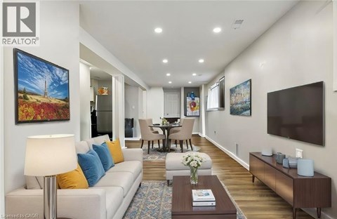 A living room with a white couch and a painting on the wall.