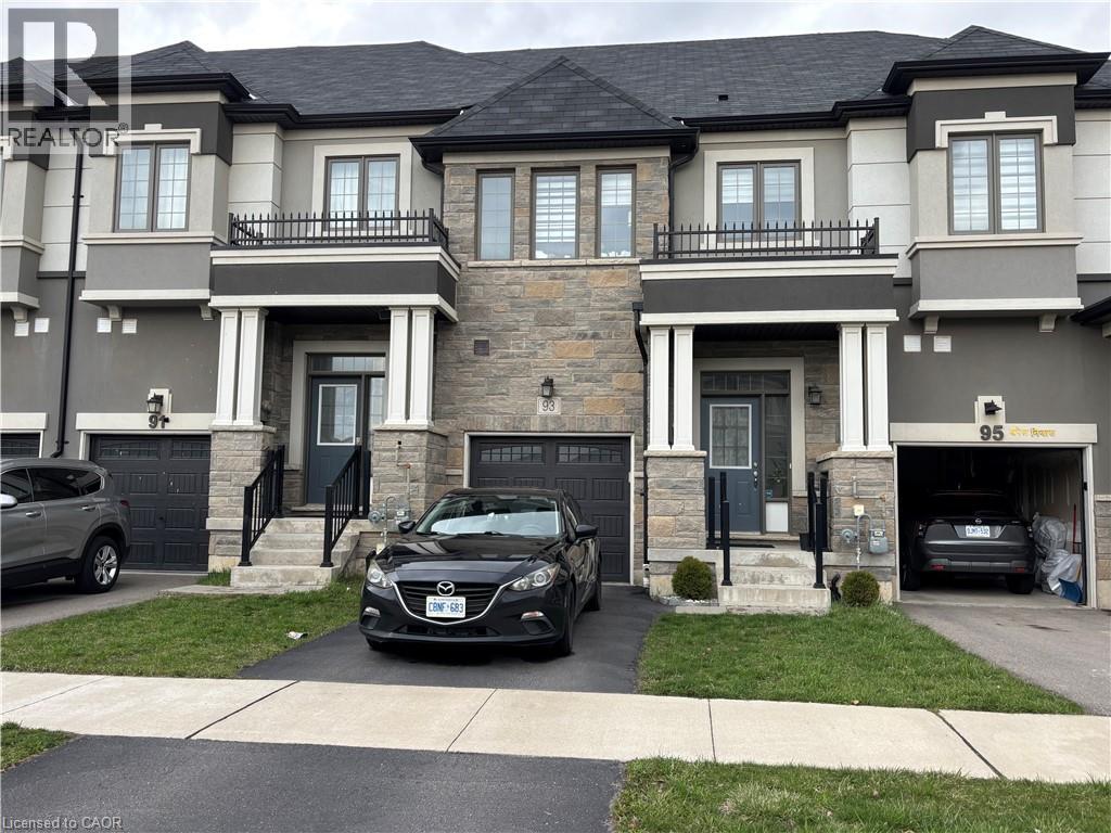 A black car is parked in front of a two-story house.