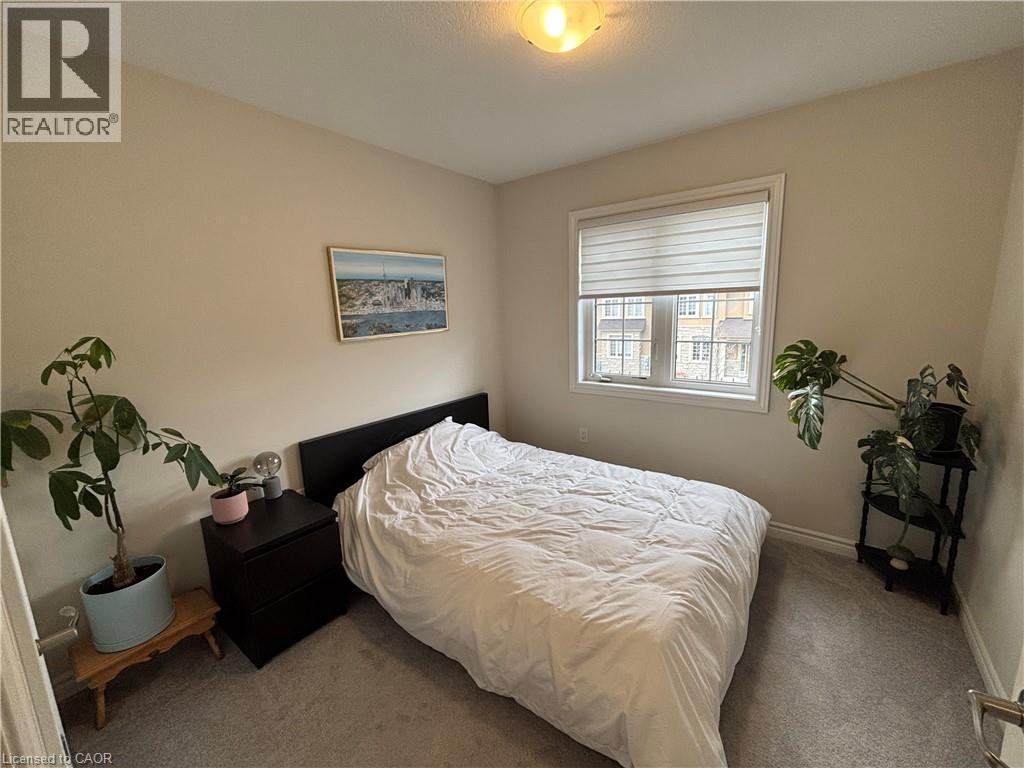 A bedroom with a bed, nightstand, and two potted plants.