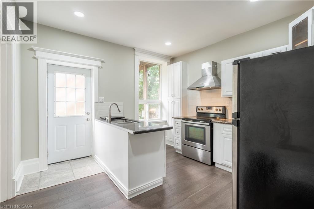A kitchen with white cabinets and a black refrigerator.