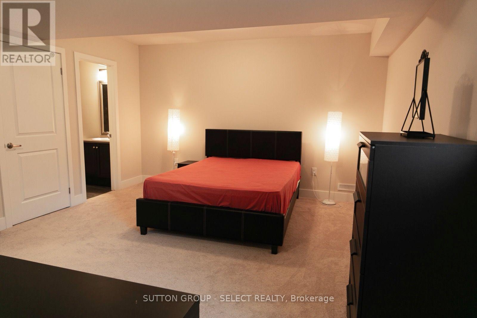 A bedroom with a red bedspread and a black bed frame.