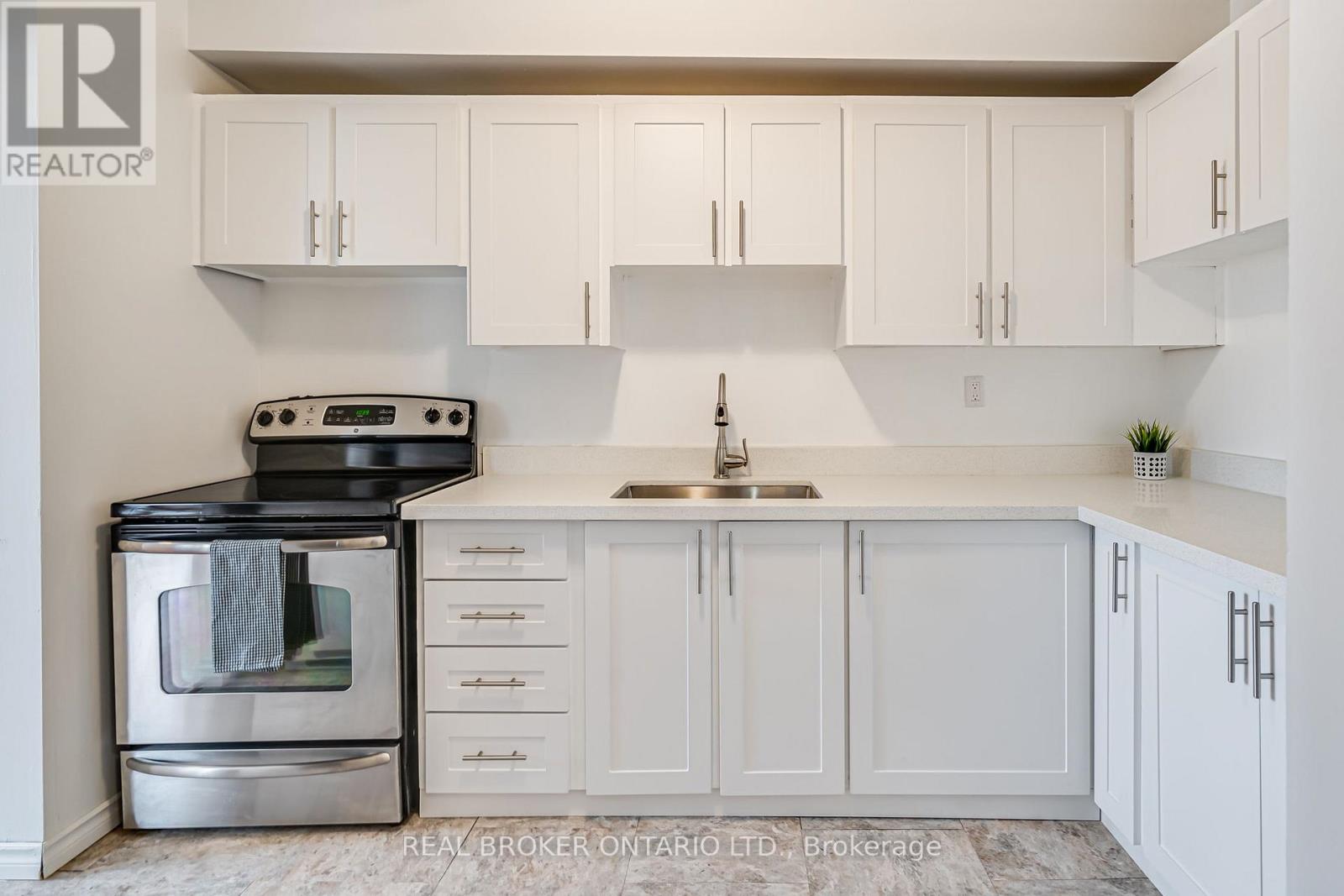 A white kitchen with a black stove top oven and a silver oven underneath.