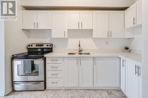 A white kitchen with a black stove top oven and a silver oven underneath.