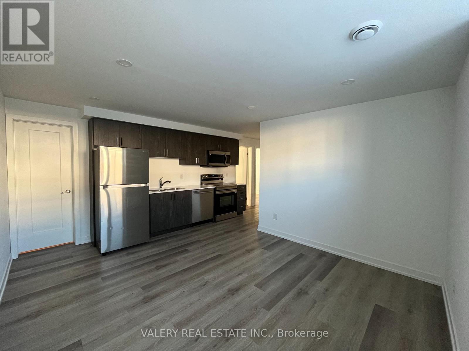 A kitchen with a refrigerator, sink, and cabinets is shown in a real estate listing.