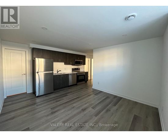A kitchen with a refrigerator, sink, and cabinets is shown in a real estate listing.