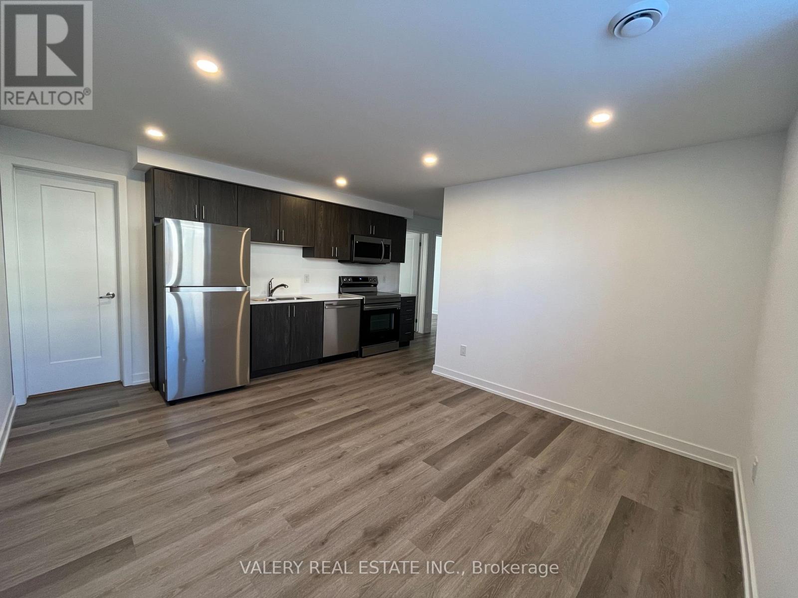 A kitchen with a refrigerator, microwave, and oven.
