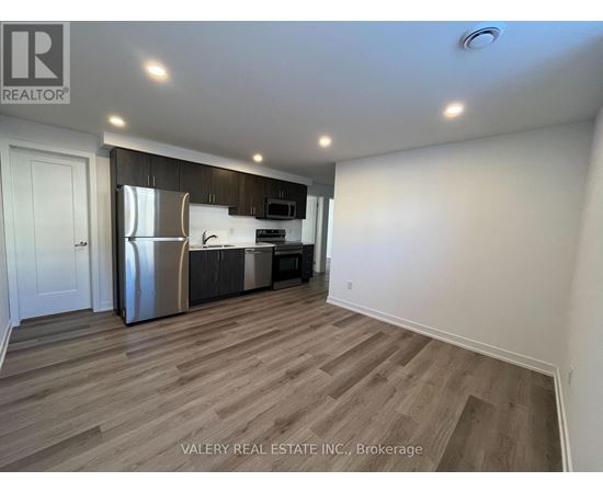 A kitchen with a refrigerator, microwave, and oven.