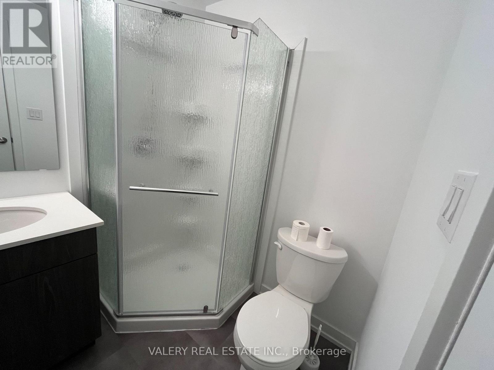 A bathroom with a toilet, sink, and shower.