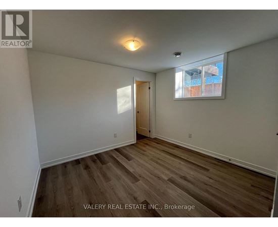 A room with wooden flooring and a window with a view of a building outside.