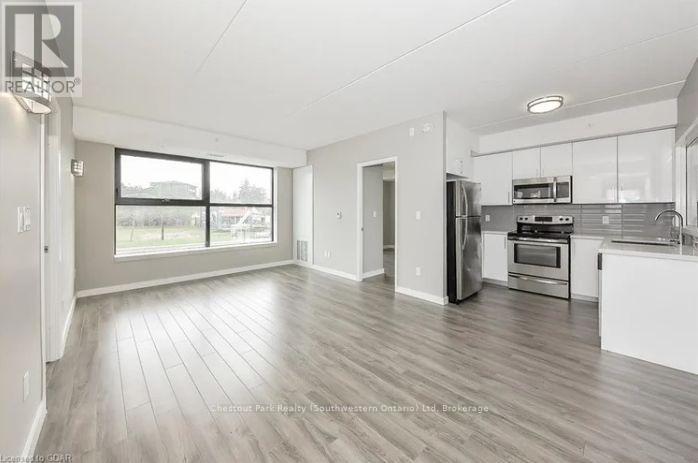 A spacious kitchen and living room with wood flooring and white walls.