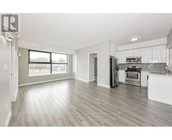 A spacious kitchen and living room with wood flooring and white walls.