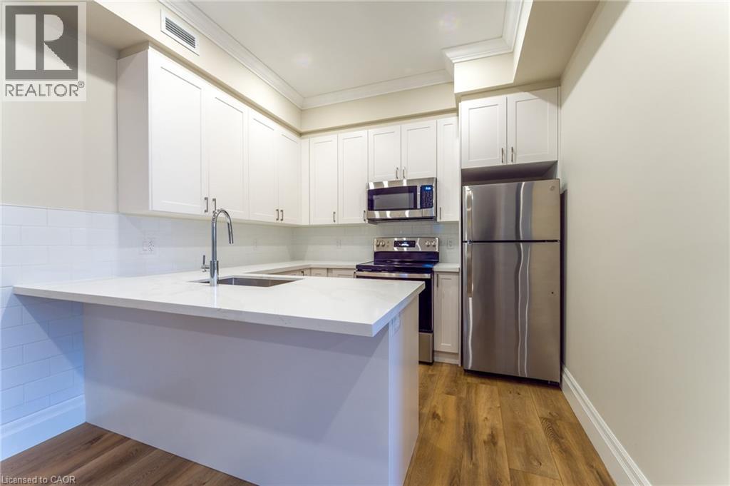 A kitchen with white cabinets and a stainless steel refrigerator.