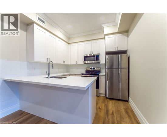 A kitchen with white cabinets and a stainless steel refrigerator.