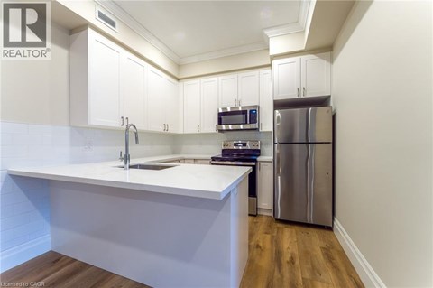 A kitchen with white cabinets and a stainless steel refrigerator.