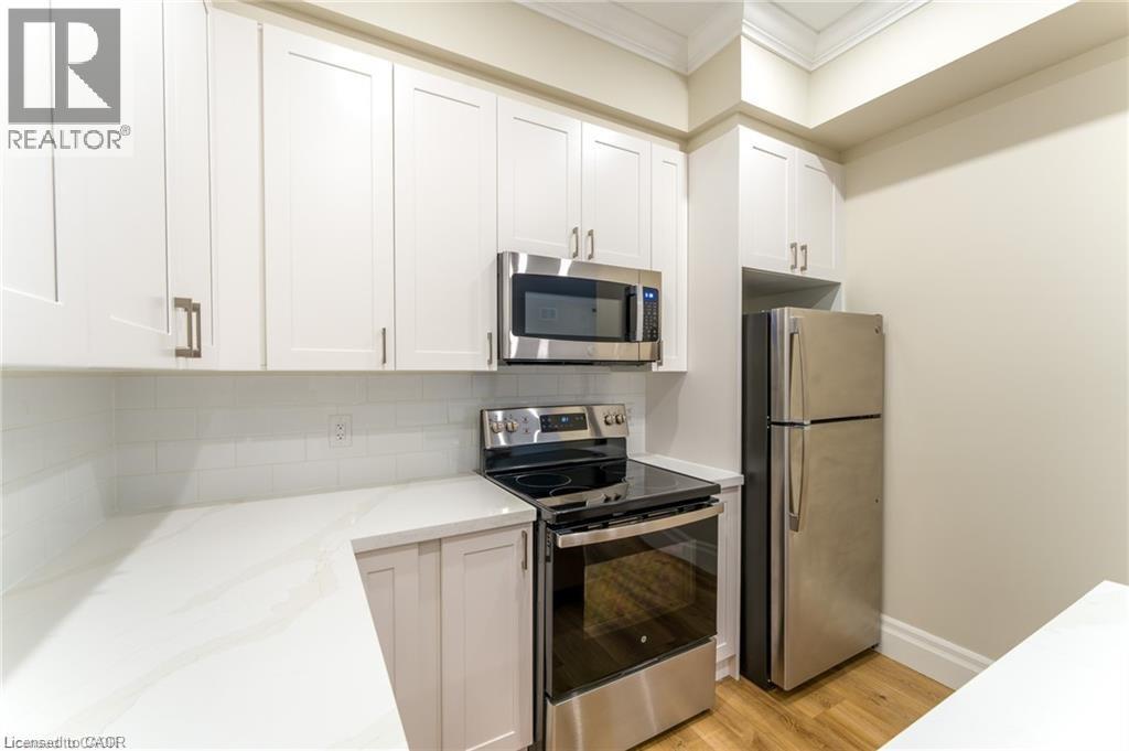 A kitchen with white cabinets and a stainless steel refrigerator.