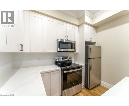 A kitchen with white cabinets and a stainless steel refrigerator.