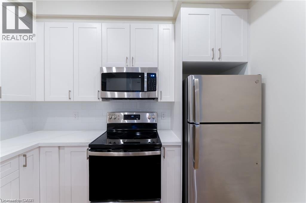 A kitchen with white cabinets and a stainless steel refrigerator.