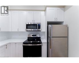 A kitchen with white cabinets and a stainless steel refrigerator.