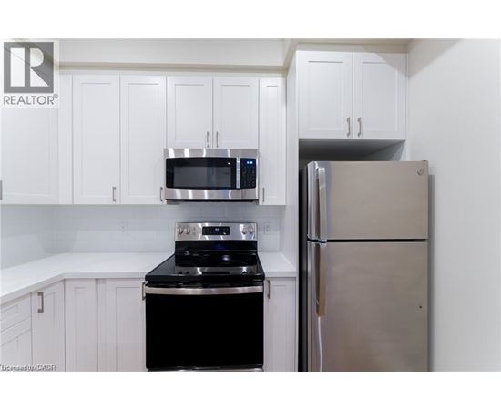 A kitchen with white cabinets and a stainless steel refrigerator.