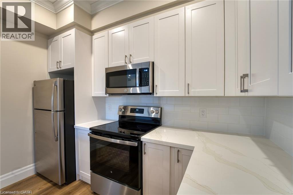 A kitchen with white cabinets and a stainless steel refrigerator.