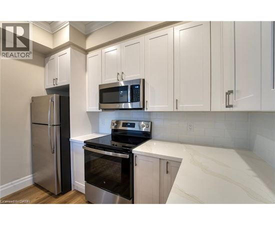 A kitchen with white cabinets and a stainless steel refrigerator.