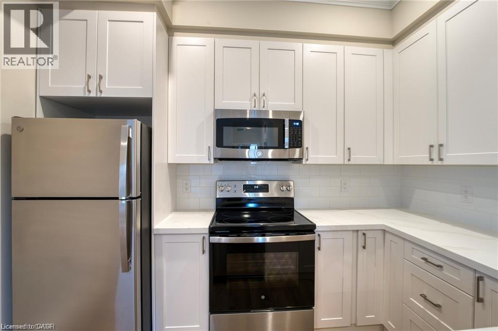 A kitchen with white cabinets and a stainless steel refrigerator.