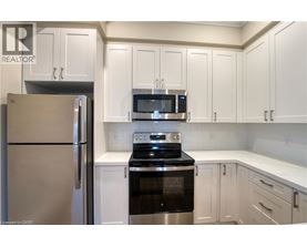 A kitchen with white cabinets and a stainless steel refrigerator.