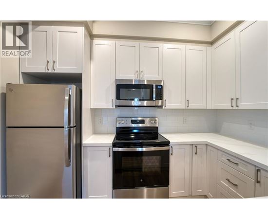 A kitchen with white cabinets and a stainless steel refrigerator.