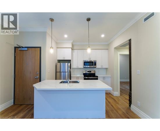 A modern kitchen with a white island and wooden floors.