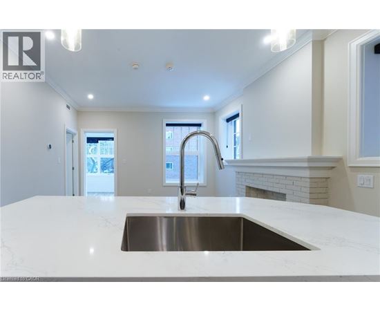 A modern kitchen with a stainless steel sink and white countertops.