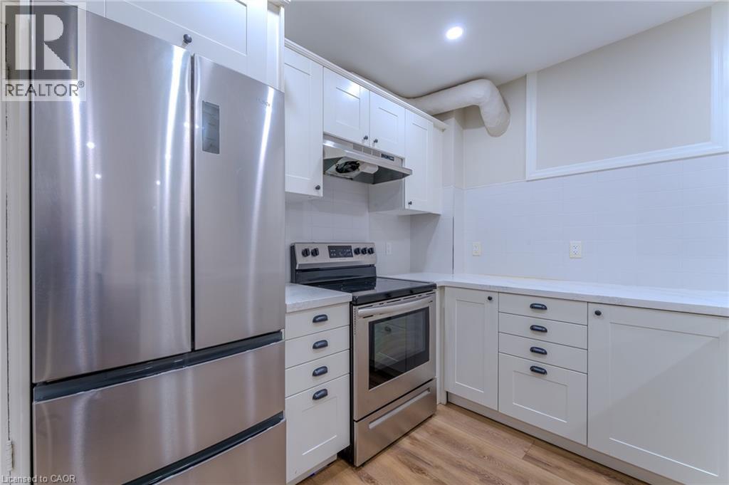 A modern kitchen with a stainless steel refrigerator and white cabinets.