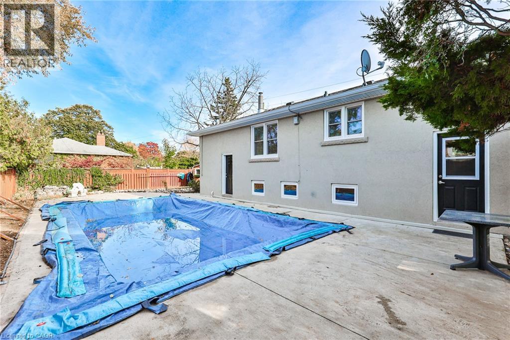 A backyard with a swimming pool covered in a blue tarp.