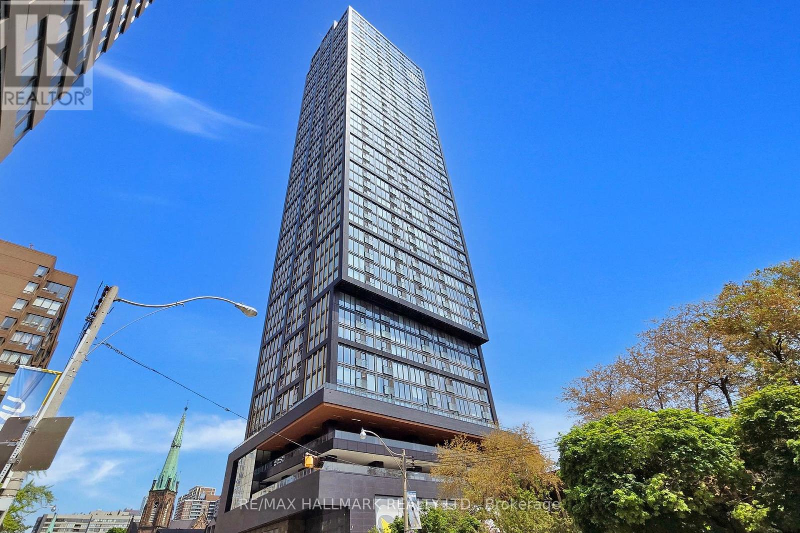A tall building with many windows is surrounded by trees and other buildings.