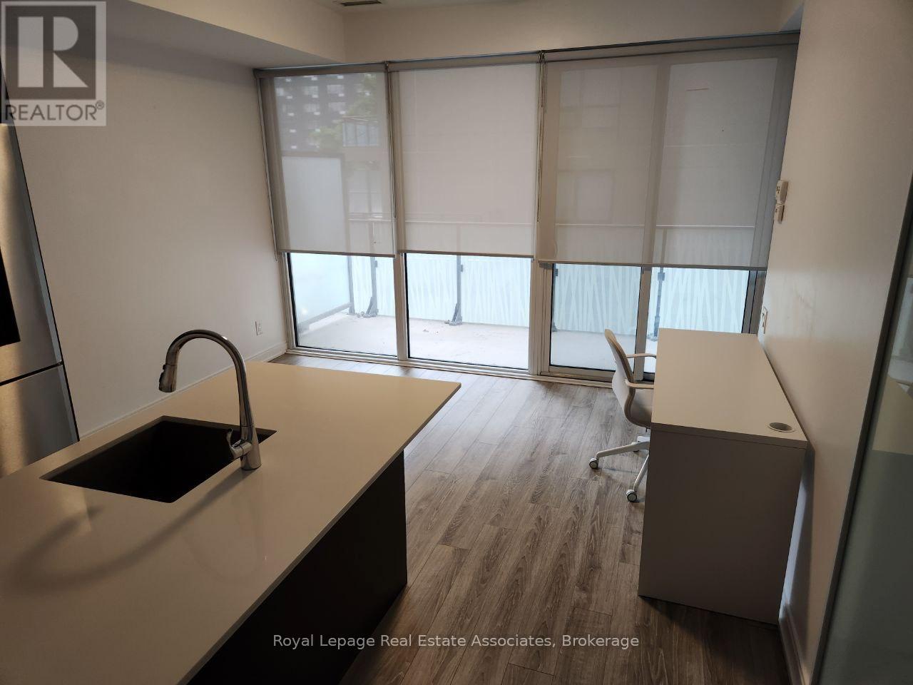 A kitchen with a sink and a window with blinds.