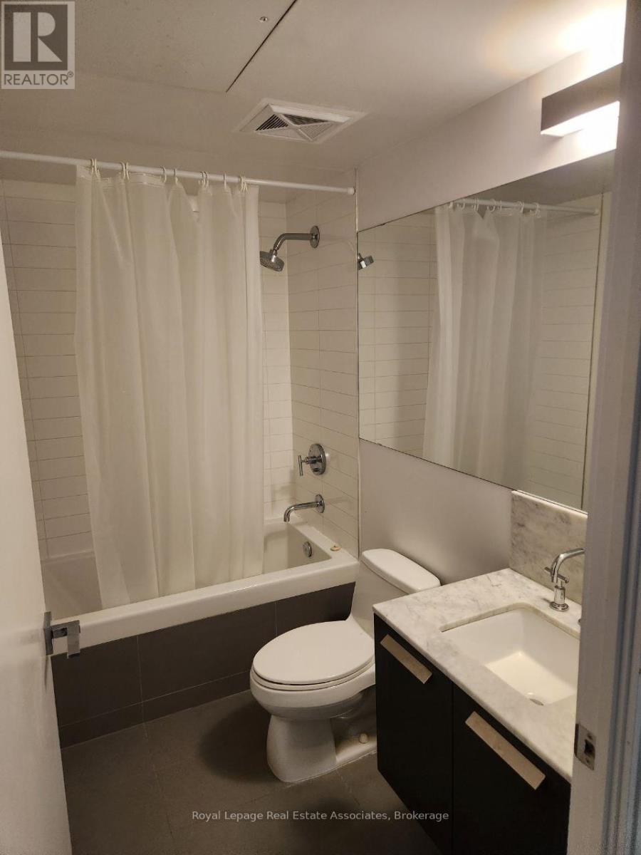 A white toilet sits in a bathroom next to a sink.