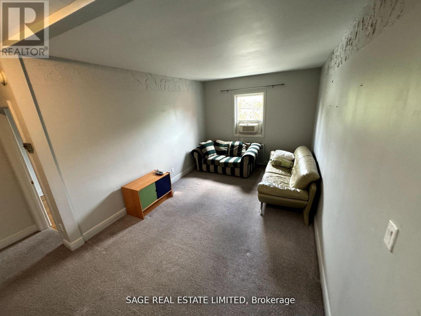 A living room with a sofa, a window, and a wooden box on the floor.