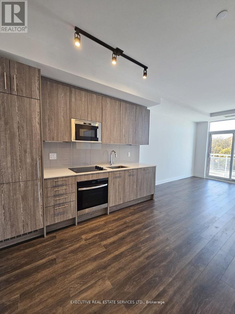 A modern kitchen with wooden cabinets and a microwave built into the cabinetry.